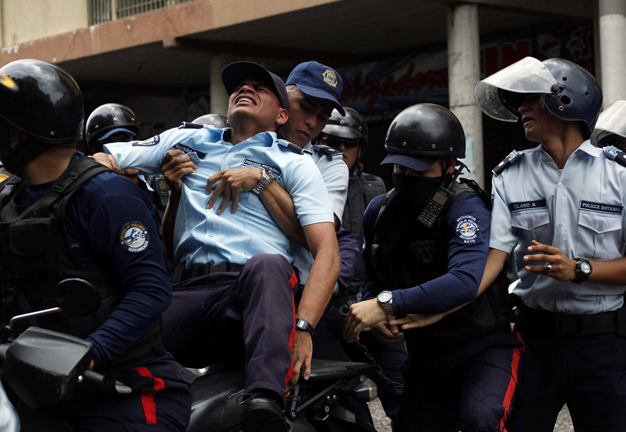 Полиция помогает травмированному коллеге во время столкновений с сторонниками оппозиции в Сан-Кристобале, Венесуэла, 19 апреля, 2017.