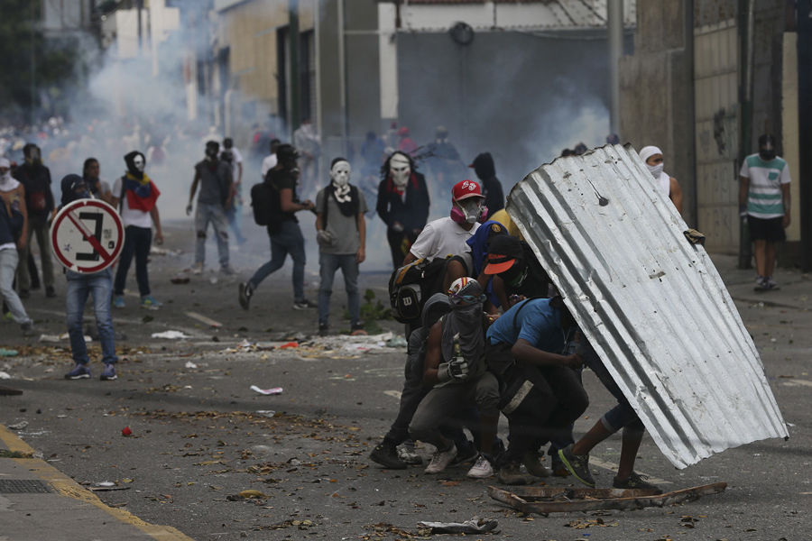 Демонстранты укрываются куском гофрированной кровли во время антиправительственных протестов в Каракасе 19 апреля 2017.