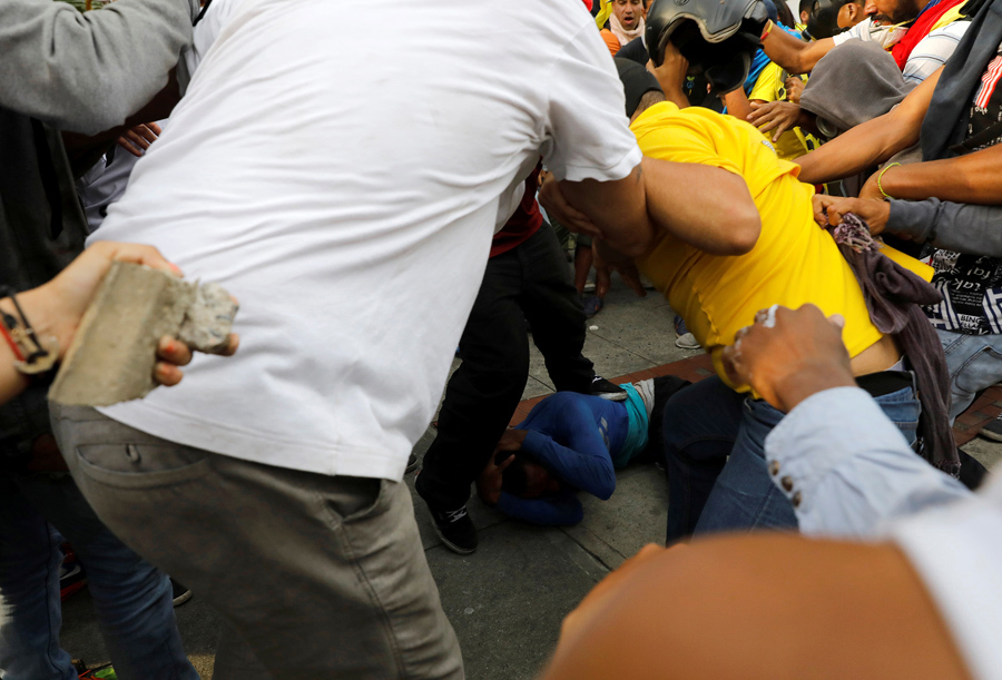 Демонстранты бьют человека, которого они обвинили в воровстве (на земле), Каракас, 19 апреля 2017.