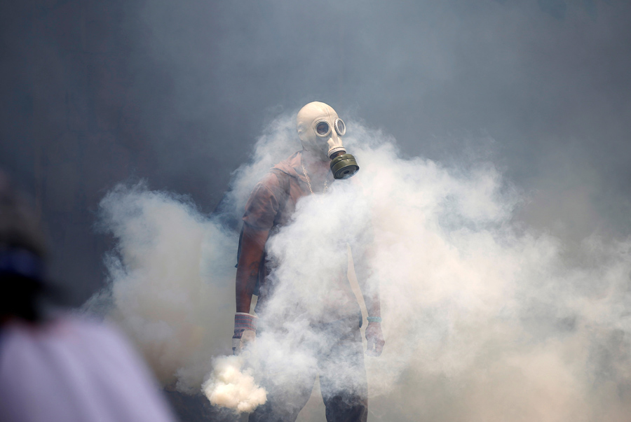 Протестующий держит баллончик со слезоточивым газом во время столкновений с полицией в Каракасе, Венесуэла, 19 апреля, 2017.