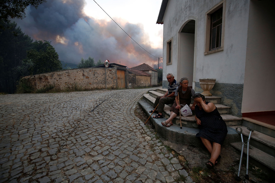 Сельчане сидят на улице во время лесного пожара возле села Fato, центральной Португалии, 18 июня, 2017. 