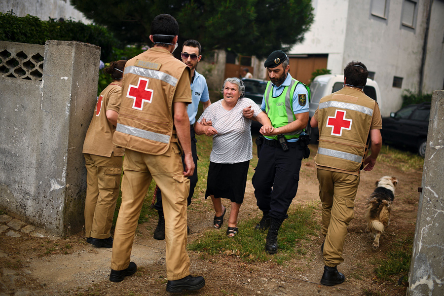 Красный Крест и сотрудники полиции эвакуируют людей из домов, 18 июня 2017 года.