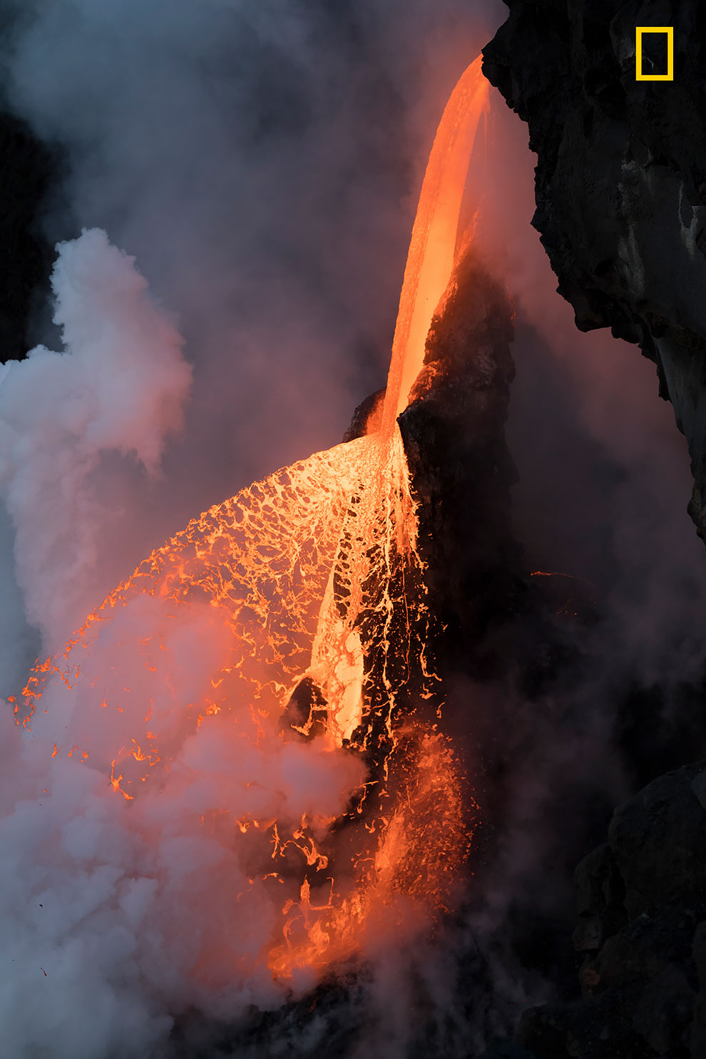 Незадолго до сумерек в Калапане, Гавайи, фрагмент охлажденной лавы откололся, распыляя лавовый поток подобно огненному аэрозолю.
